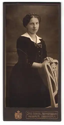 Fotografie Otto Hertel, Freiberg i./S., Erbischestr. 11, Junge Dame mit geflochtenen Haaren posiert mit Stuhl