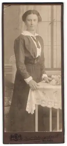 Fotografie Kurt Behringschmidt, Wilkau i. S., Junge Dame in dunklem Kleid mit weisser Bluse hält einen Blumenstrauss