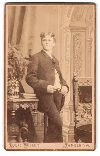 Fotografie Louis Müller, Hameln a. W., Münsterkirchhof 5, Portrait charmanter junger Mann mit lockigem Haar im Anzug