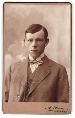 Fotografie A. Berns, Uddevalla, Portrait junger Herr mit Seitenscheitel u. Fliege im Anzug