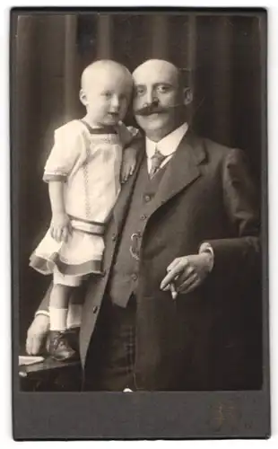 Fotografie Fotograf und Ort unbekannt, Mann mit prächtigem Schnauzbart und seinem Kind