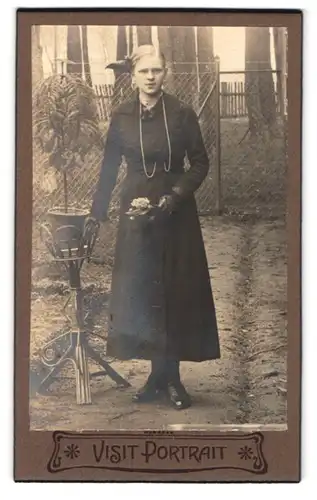 Fotografie Fotograf und Ort unbekannt, Portrait Dame mit Schleife im Haar und Blumen in der Hand