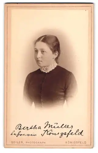 Fotografie Seiler, Königsfeld, Junge Dame mit zurückgebundenen Haaren trägt Schwarzes Kleid mit Zierkragen