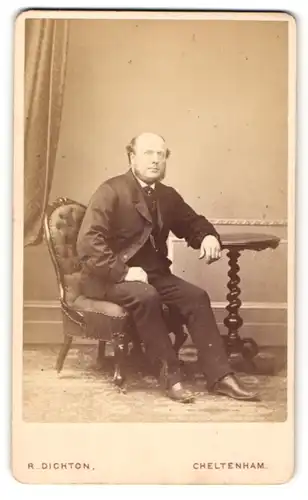 Fotografie R. Dighton, Cheltenham, Mann mit Halbglatze und Bart im Anzug auf Sessel sitzend