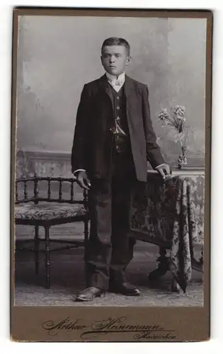 Fotografie Arthur Heinemann, Hainichen in Sachsen, Portrait junger Herr im Anzug mit Büchern an Tisch gelehnt