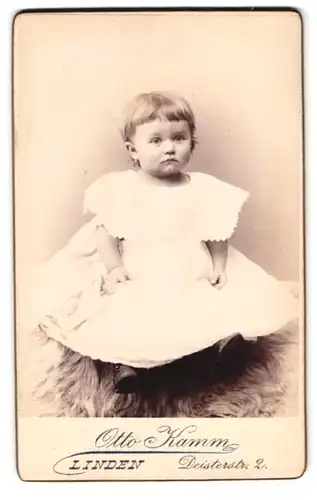 Fotografie Otto Kamm, Linden, Deisterstrasse 2, kleines Mädchen im weissen Kleid sitzt auf Fell