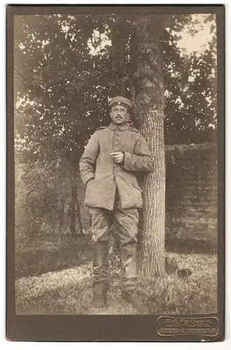 Fotografie E. G. Fr. Stotz, Dresden, Leipzigerstrasse 49, Soldat in Feldgrau lehnt an einem Baum