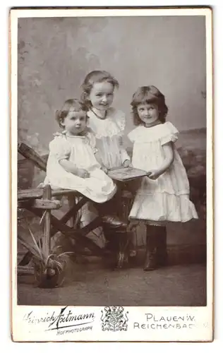 Fotografie Heinrich Axtmann, Plauen i. V., Portrait drei bezaubernde Mädchen mit Buch in den Händen