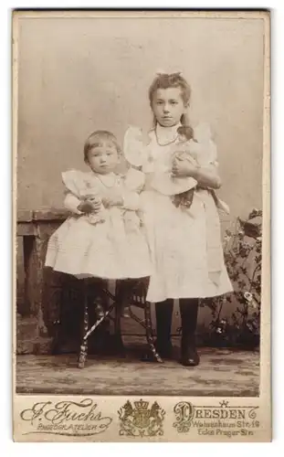 Fotografie J. Fuchs, Dresden, Waisenhausstr., Portrait zwei niedliche Mädchen mit Spielzeug im Arm