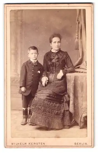 Fotografie Wilhelm Kersten, Berlin, Krausenstr. 40, Portrait stolze Mutter im Kleid & frecher Bube im Anzug