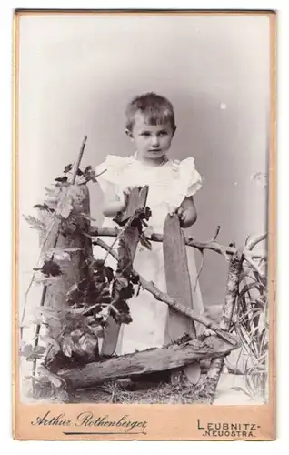 Fotografie Arthur Rothenberger, Leubnitz-Neuostra, Portrait süsses Mädchen im weissen Kleidchen am Holzzaun stehend