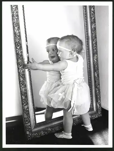 Fotografie niedliches Baby will sein Spiegelbild umarmen