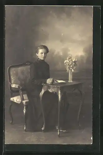Foto-AK schöne Frau mit Buch an einem Tisch sitzend