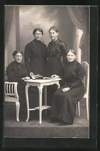 Foto-AK Vier bildschöne junge Frauen vor einer Studiokulisse am Tisch sitzend und stehend