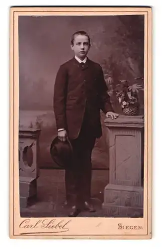 Fotografie Carl Siebel, Siegen, am Bahnhof, Portrait elegant gekleideter Junge mit Hut in der Hand