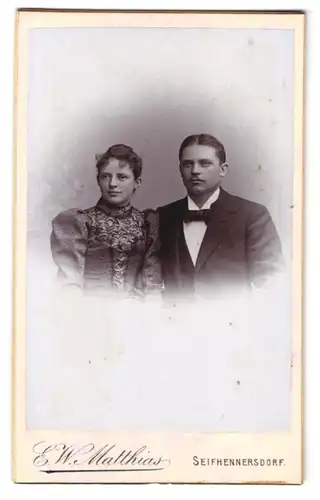 Fotografie E. W. Matthias, Seifhennersdorf i. S., Paar im Anzug und Kleid mit Locken