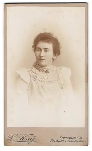 Fotografie L. Kny, Ebersbach i. S., Portrait Dame im weissen Kleid mit Brosche und Locken