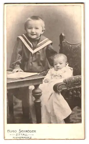 Fotografie Hugo Schröder, Zittau, Milchstr. 7, Portrait Junge im Matrosenanzug mit Kleinkind im Kleid auf dem Stuhl