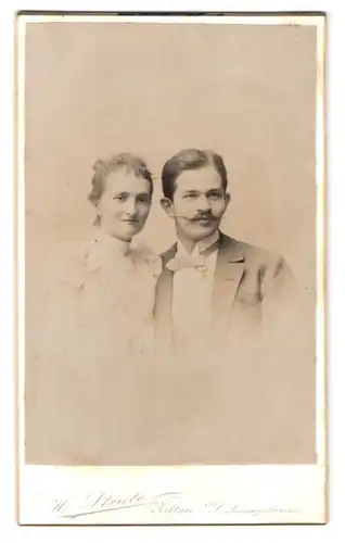 Fotografie H. Strube, Zittau, Lessingstr. 14, Portrait junges Paar im Anzug mit Zwirbelbart und weissem Kleid