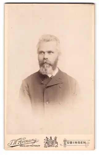 Fotografie J. W. Hornung, Tübingen, Uhlandstr. 11, Portrait Mann im Anzug mit Vollbart schaut verlegen