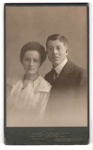 Fotografie Louis Schindhelm, Ebersbach i. S., Portrait Parr im Anzug mit Zwickerbrille und Frau im Kleid mit Halskette
