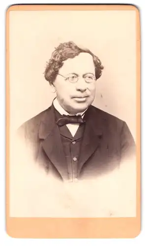 Fotografie Quido Trapp, Brünn, gross. Platz 6, Portrait Herr im Anzug mit Brille und Locken trägt Fliege