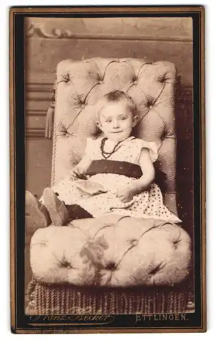 Fotografie Franz Becker, Ettlingen, Portrait Mädchen im Pünktchenkleid mit Perlenkette sitzt im Sessel