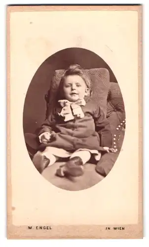 Fotografie W. Engel, Wien, Alserhauptstr. 27, Portrait kleiner Junge im Kleid mit Schleife