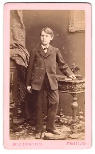 Fotografie Emile Schweitzer, Strasbourg, Place Kleber 7, Portrait junger Knabe im Anzug mit Fliege posiert im Atelier