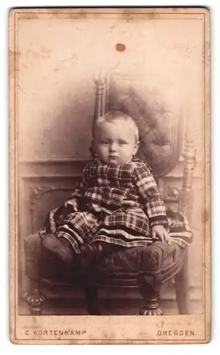 Fotografie C. Kortenkamp, Dresden, Annenstr. 10, Portrait Kleinkind im karierten Kleid auf einem Stuhl sitzend