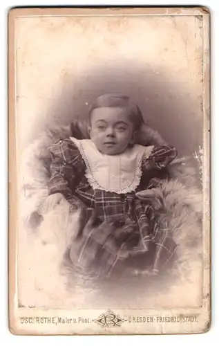 Fotografie osc. Rothe, Dresden, Schäferstr. 37, Portrait Kleinkind im karierten Kleid mit Sabberlatz