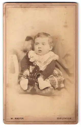 Fotografie Wilhelm Mayer, Esslingen, Portrait dickes Kleinkind im karierten Kleid mit Spitzenkragen