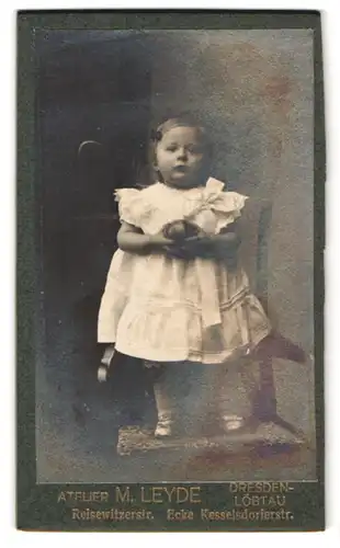 Fotografie M. Leyde, Dresden, Reisewitzerstr., Portrait kleines Mädchen im weissen Kleid mit Ball in der Hand