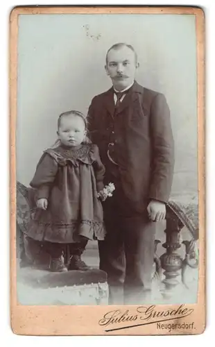 Fotografie Julius Grusche, Neugersdorf i. S., Portrait Vater im Anzug mit kleiner Tochter im Kleid und Haarreifen
