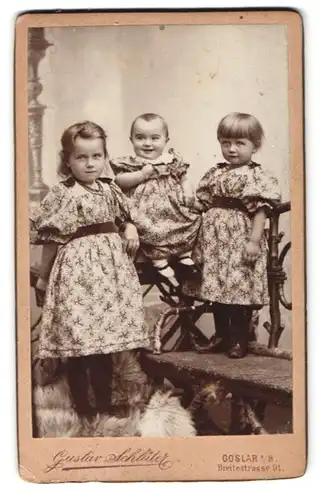 Fotografie Gustav Schlüter, Goslar a. H., Breitestr. 91, Portrait drei Kinder in Blümchenkleidern posieren im Atelier