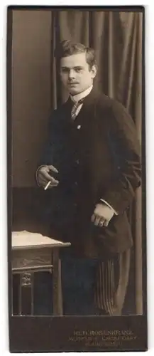 Fotografie Rud. Rosenkranz, Mügeln, Königstr. 32, Portrait junger Mann im Anzug mit Zigarette im Atelier