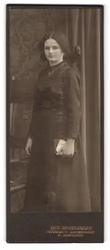 Fotografie Rud. Rosenkranz, Mügeln, Portrait junge Frau im schwarzen Kleid mit Halskette und Haarschleife