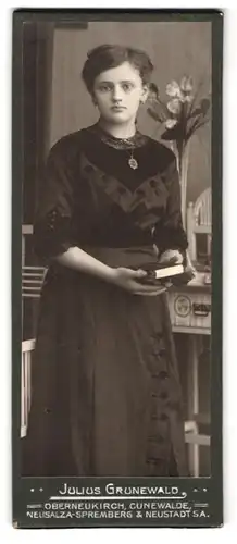 Fotografie Julius Grunewald, Oberneukirch, Portrait junge Frau im Kleid mit Bibel in der Hand schaut traurig