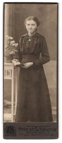 Fotografie Heinrich Schmorrde, Herrnhut, Portrait junge Frau im schwarzen Kleid mit Halskette und Buch in der Hand