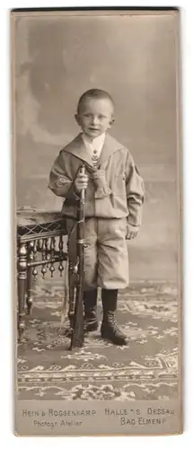 Fotografie Hein & Roggenkamp, Halle a. S., Portrait kleiner Junge Otto Rudloff mit Spielzeuggewehr im Anzug