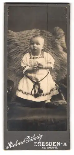 Fotografie Richard Jähnig, Dresden, Marienstr. 12, Portrait Kleinkind im hellen Kleid auf einem Fell stehend