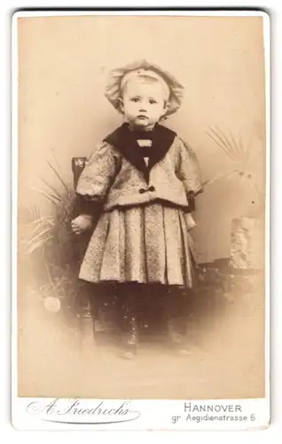 Fotografie A. Friedrichs, Hannover, gr. Aegidienstr. 6, Portrait kleines Mädchen im karierten Kleid mit Mütze