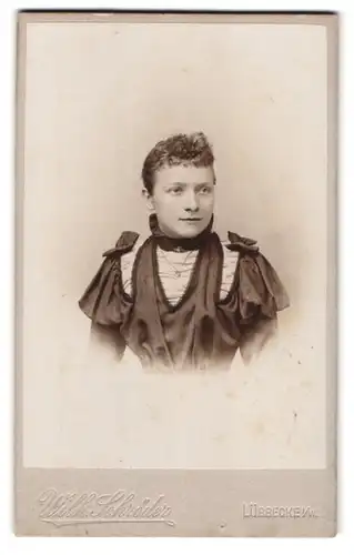 Fotografie Wilh. Schröder, Lübbecke i. W., Portrait junge Frau im verziehrten Kleid mit Locken