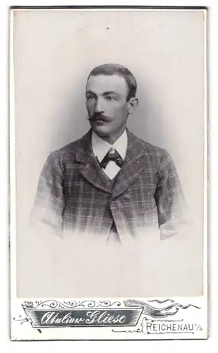 Fotografie Atelier Gliese, Reichenau i. S., Portrait Mann im karierten Anzug mit Fliege und Moustache