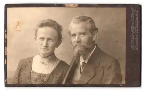 Fotografie Herm. Bähr, Dresden, Antonstr. 2, Portrait älterer Paar im Anzug mit stubbelbart und im Kleid mit Brosche