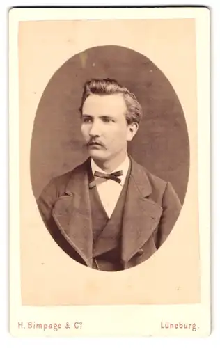 Fotografie H. Bimpage & Co., Lüneburg, Portrait junger Mann mit Schnurrbart und Fliege im Jackett