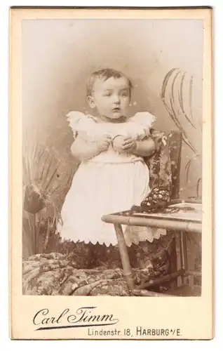 Fotografie Carl Timm, Harburg a. E., Lindenstr. 18, Portrait kleines Kind im weissen Kleid mit Ball in der Hand