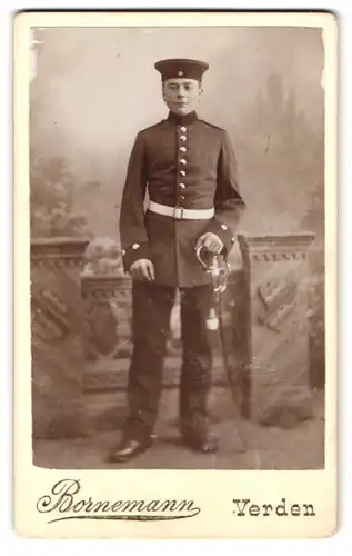 Fotografie Bornemann, Verden, Portrait junger Knabe Soldat in Uniform mit Säbel und Krätzchen