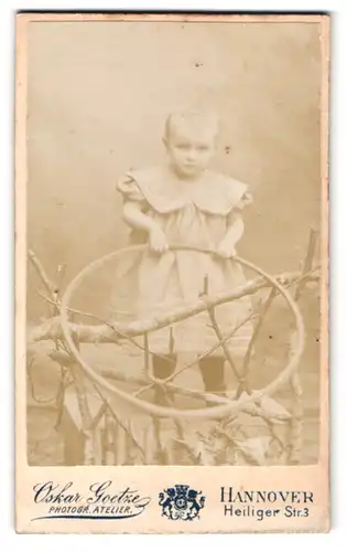 Fotografie Oskar Goetze, Hannover, Heiliger Str. 3, Portrait blondes kleines Mädchen im Kleid mit Reifen in der Hand