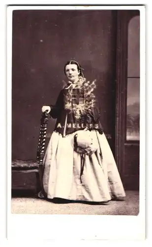 Fotografie Melliss, Liverpool, Portrait bildschönes Mädchen im prachtvollen Kleid und Hut in der Hand